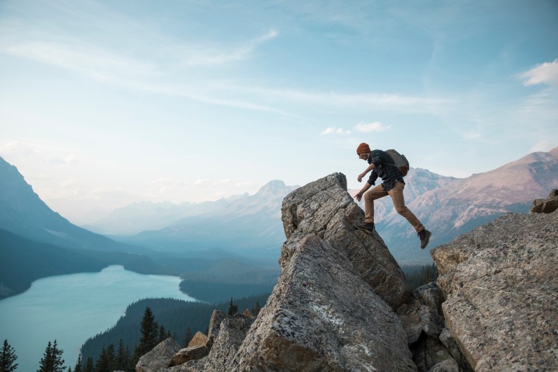 A man walking towards a rocky point overlooking a lake