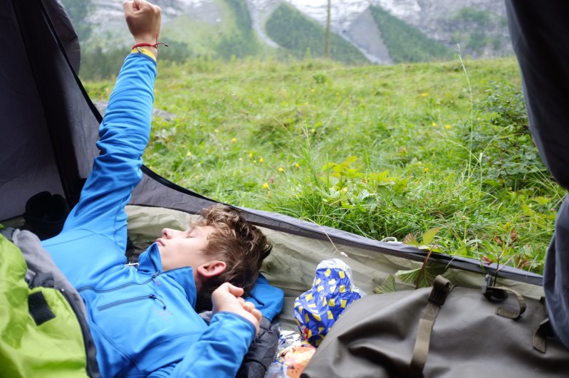 A young man sleeping in a tent.