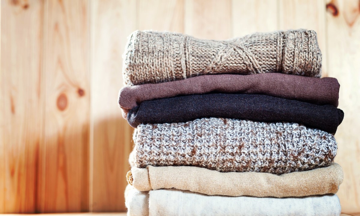 Knit cozy sweater folded in a pile on wooden background