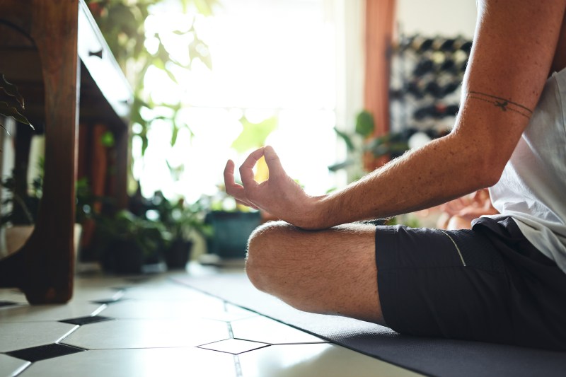 Shot of a man meditating in the lotus position at home.