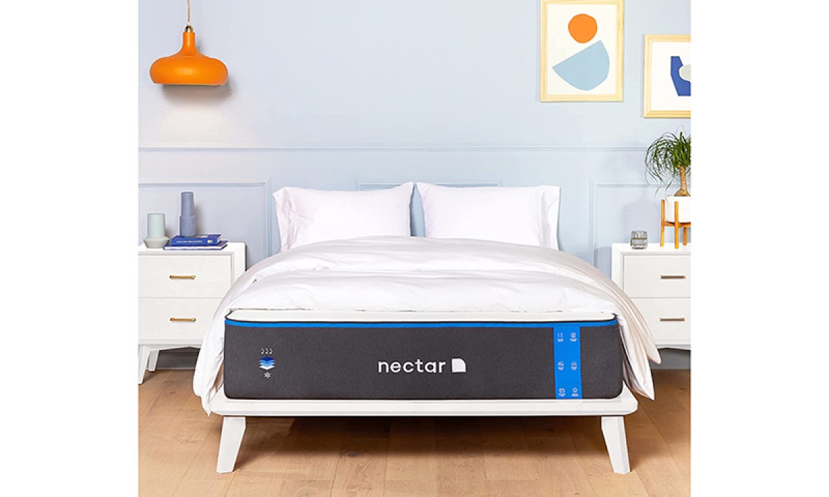 A Nectar memory foam mattress sits on a bed frame in a furnished bedroom.