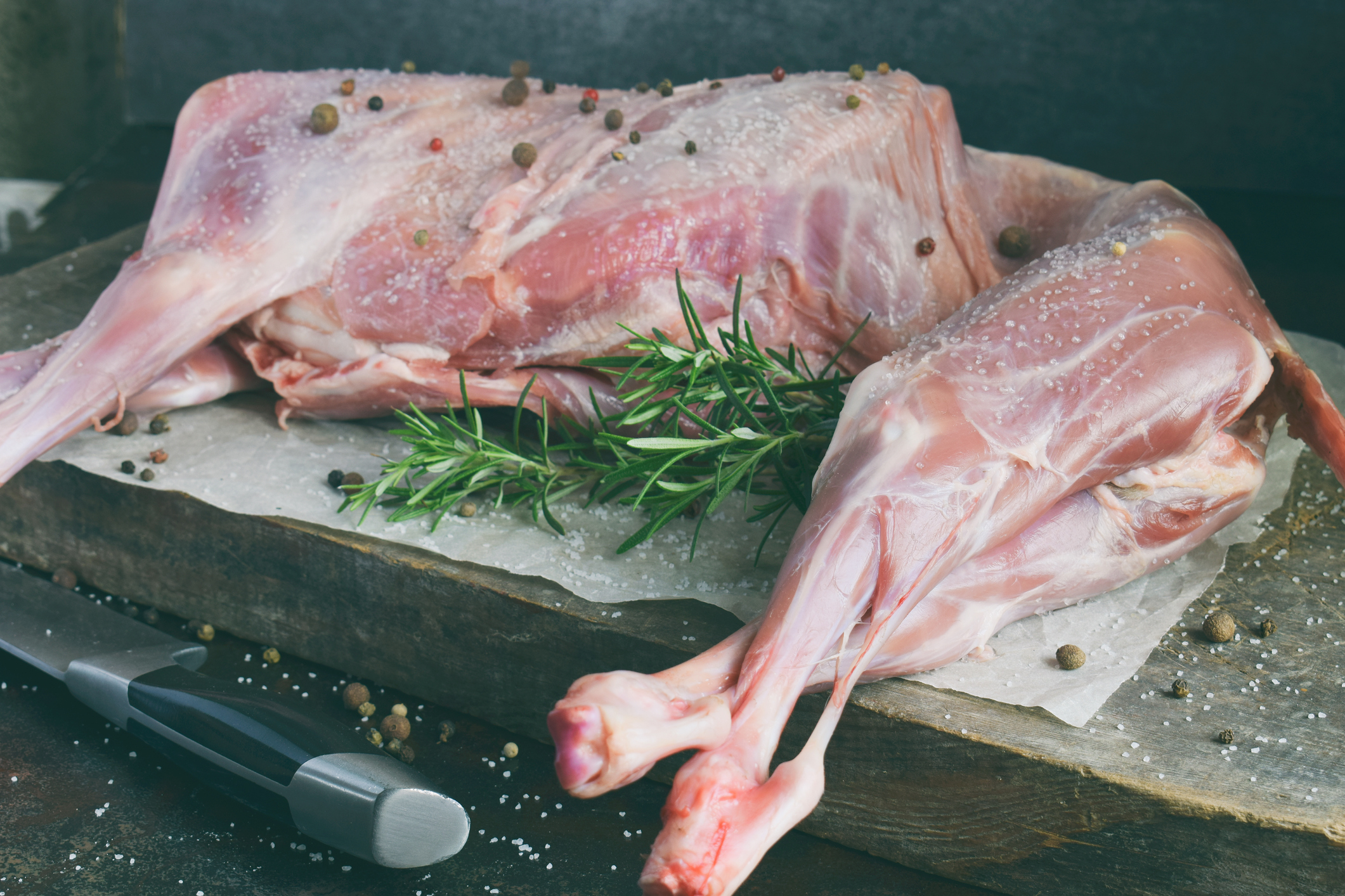 Whole raw lamb and knife on the wooden board.