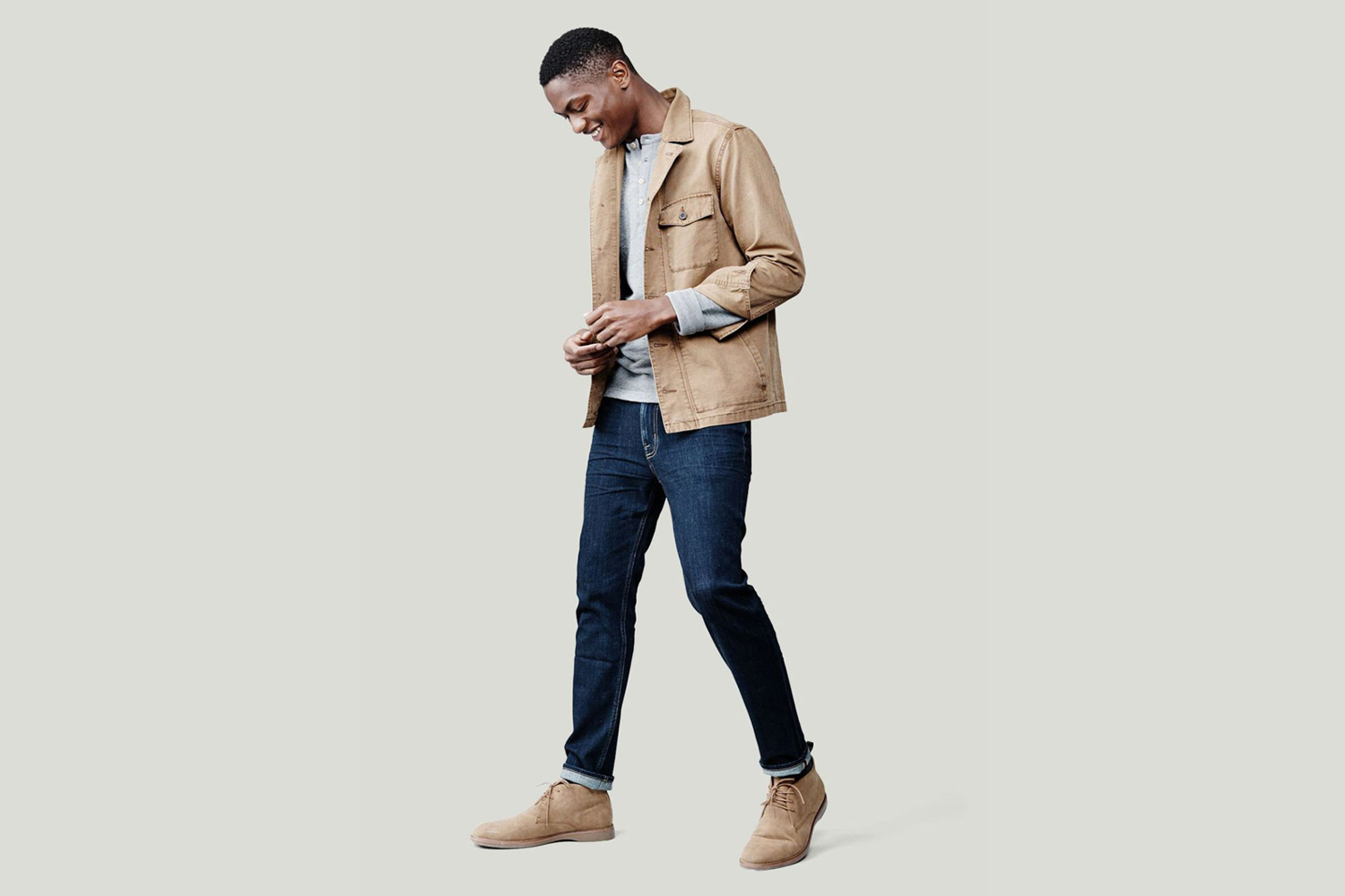 A smiling male model in smart casual attire looking at his shoes.