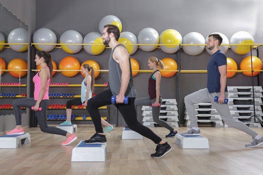 A group of young people doing weight lifting exercises in the gym.