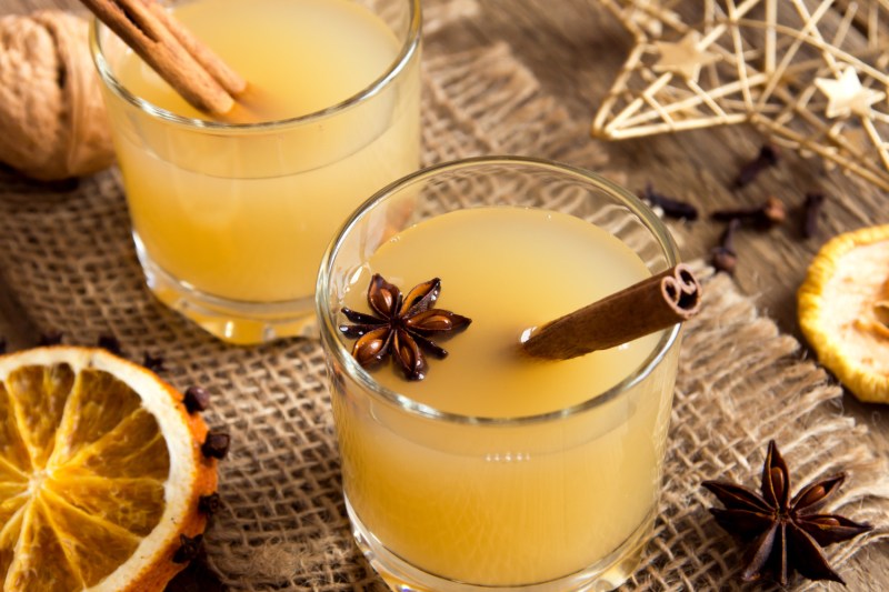 Two cups of hot toddies with cinnamon sticks on a piece of cloth.