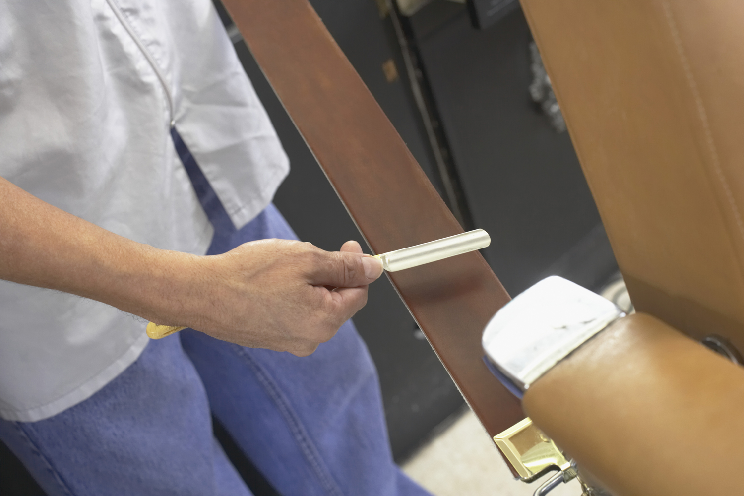A midsection of a barber sharpening a straight razor.