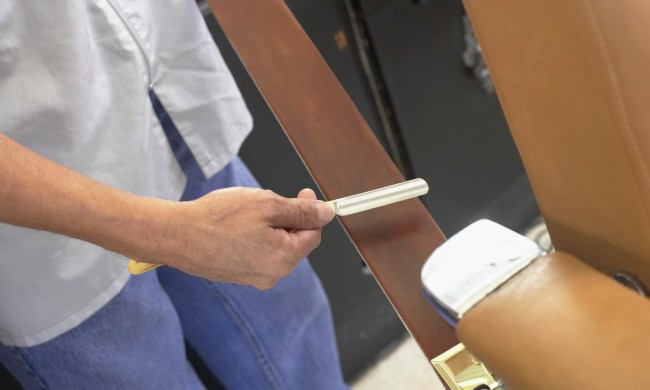 A midsection of a barber sharpening a straight razor.
