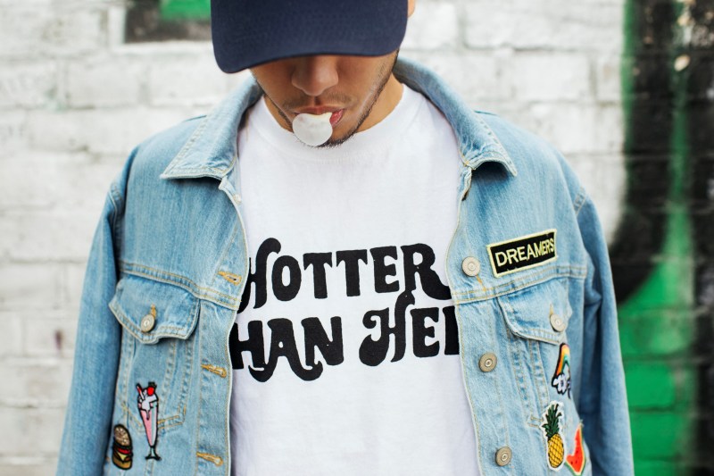 Man wearing a denim jacket over a statement shirt.