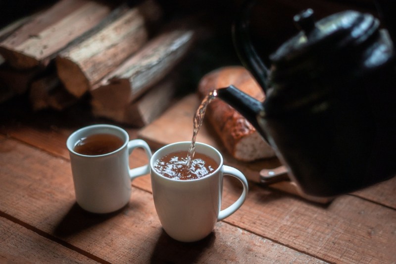 bedtime tea being poured into white ceramic mugs on a wooden table.