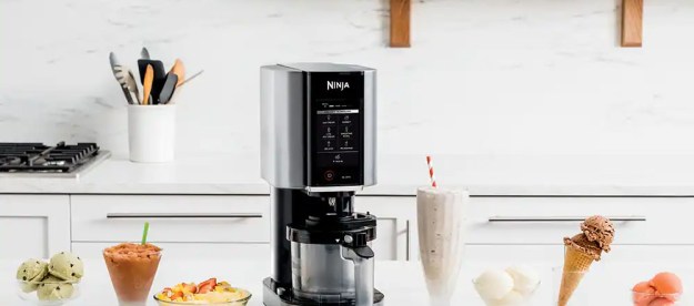 Ninja Creami Ice Cream Maker sitting on a counter with bowls of ice cream.