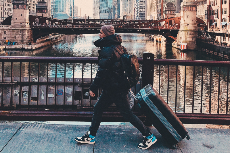Man walking with a rolling luggage in the city.