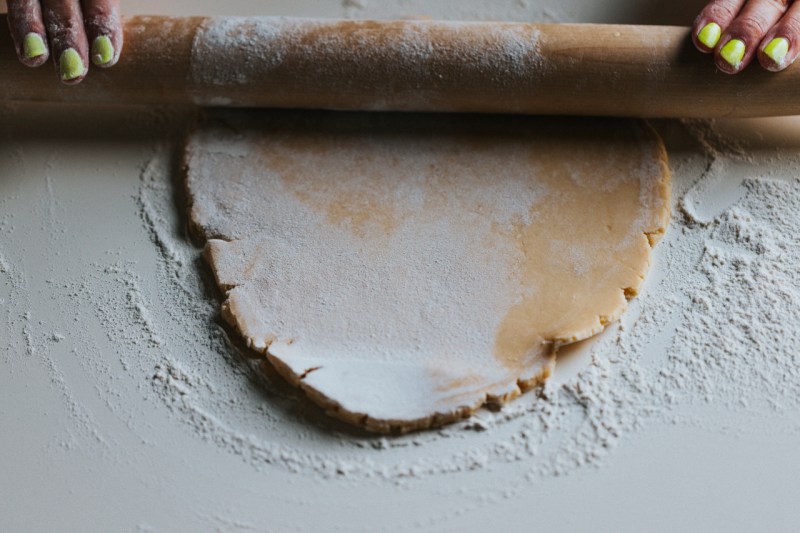 Pie crust being rolled out on a table.