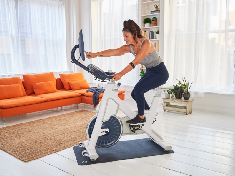 Woman working out on MYX II bike with tablet.