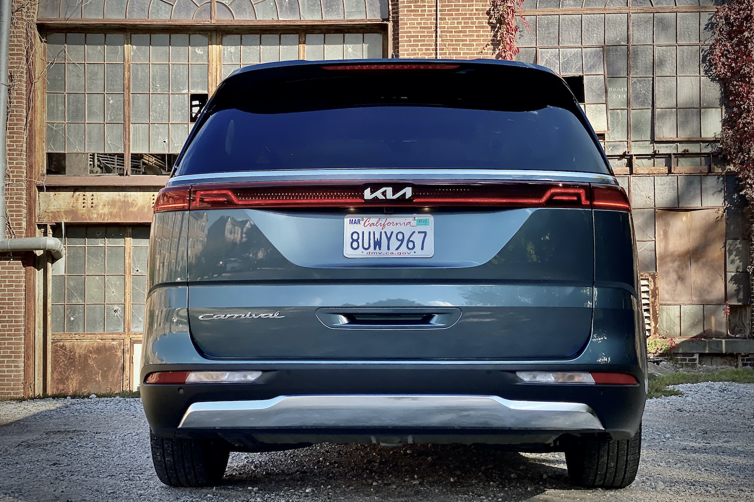 Kia Carnival rear end in front of old building.