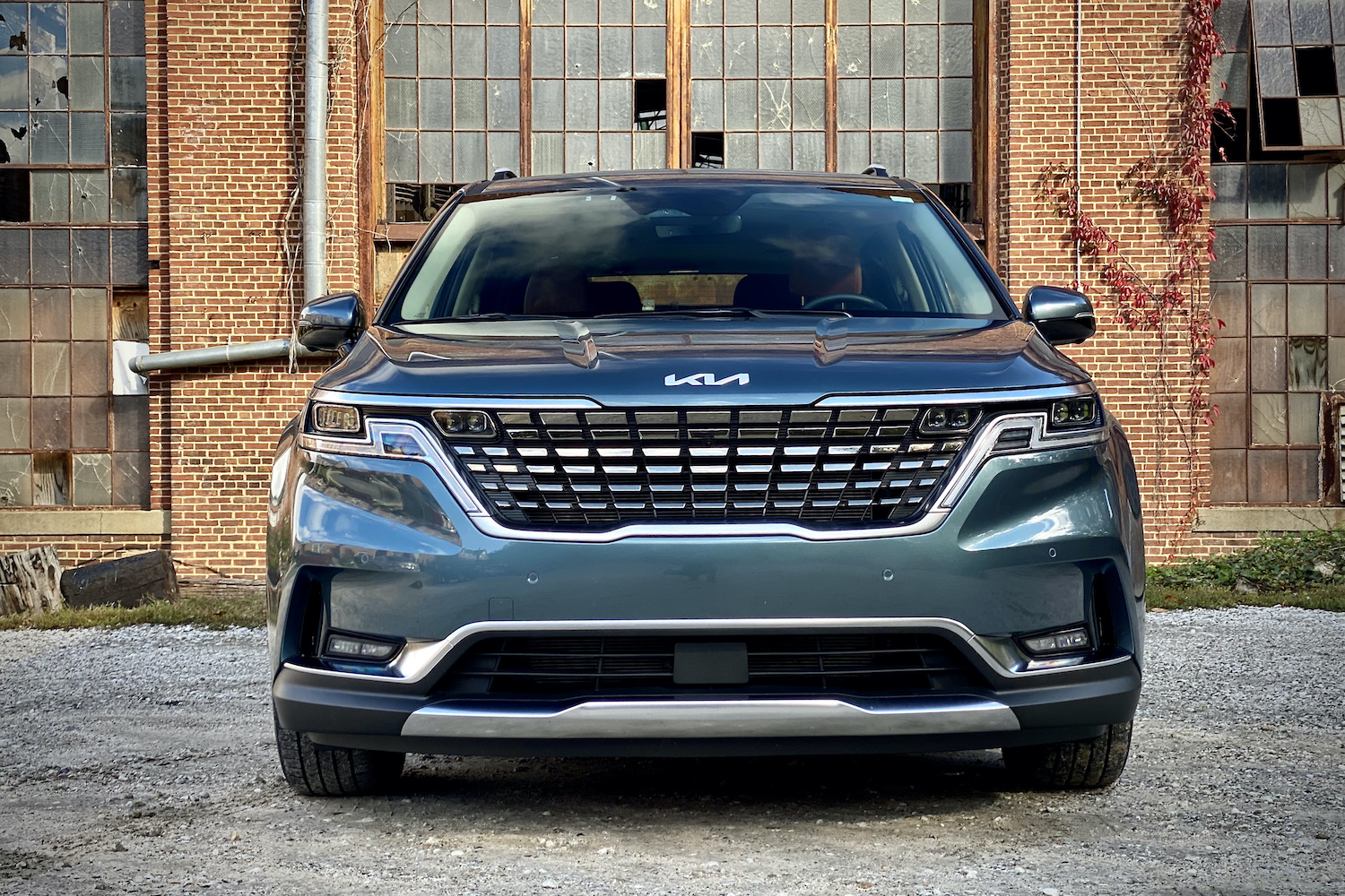 Front end of Kia Carnival with old building in the back.