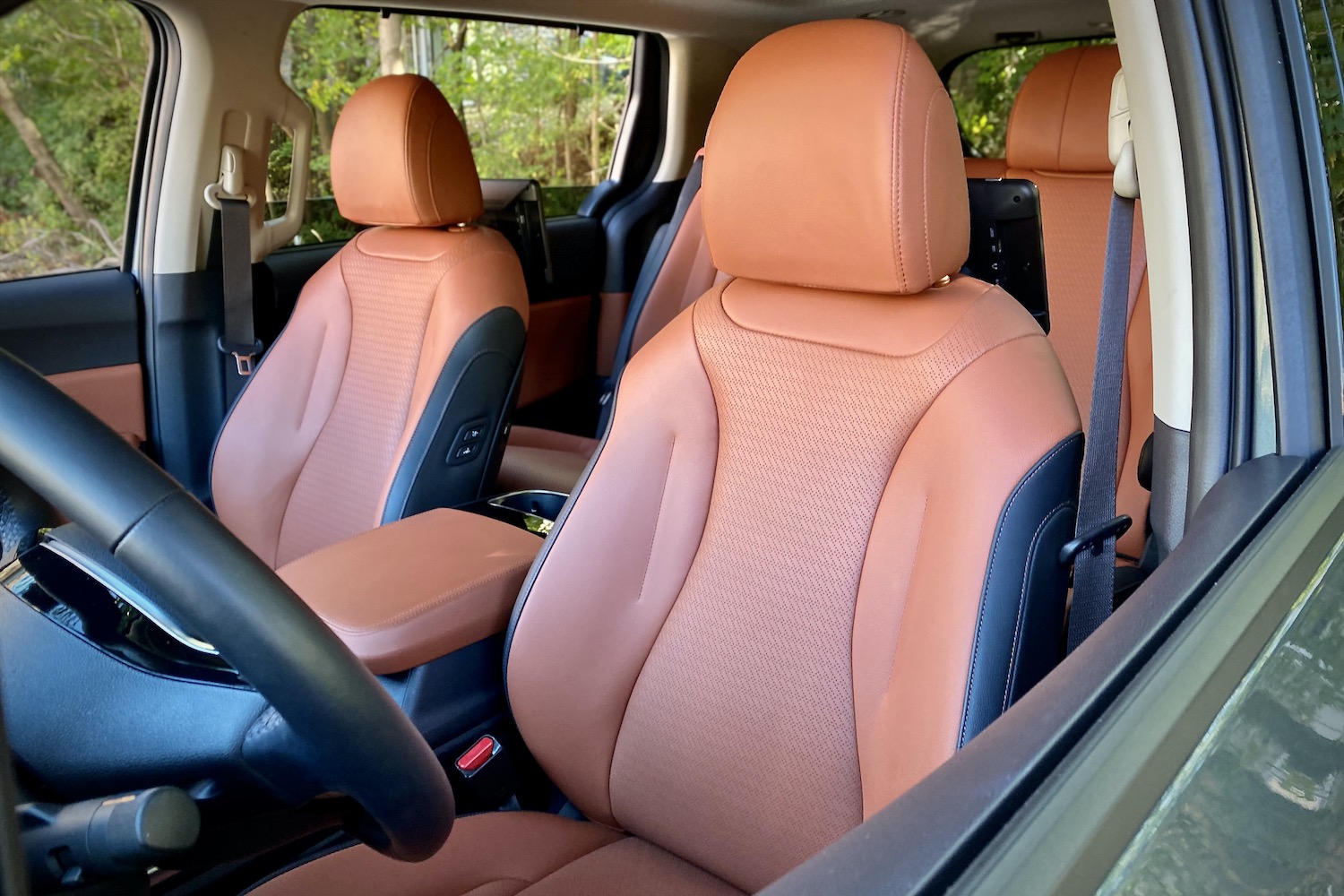 Kia Carnival driver seat with trees in the back.