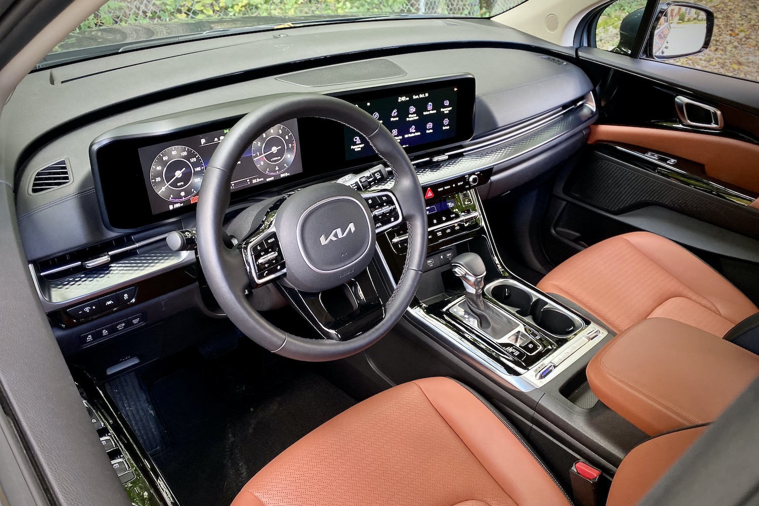 Kia Carnival dashboard close up with trees in the back.