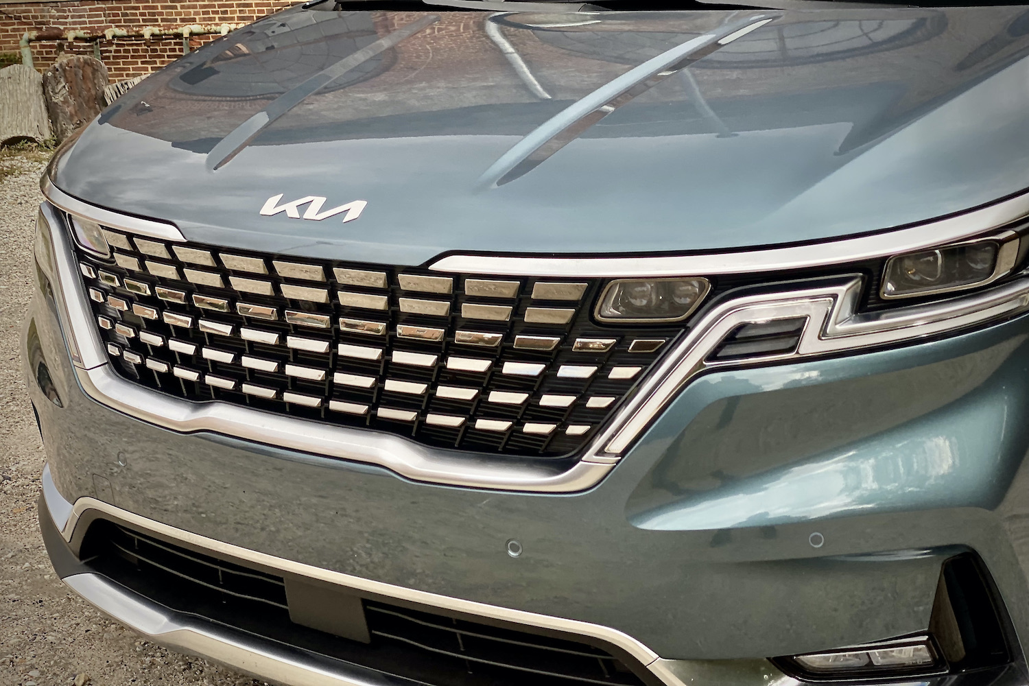 Kia Carnival grille close up with daytime running lights on.