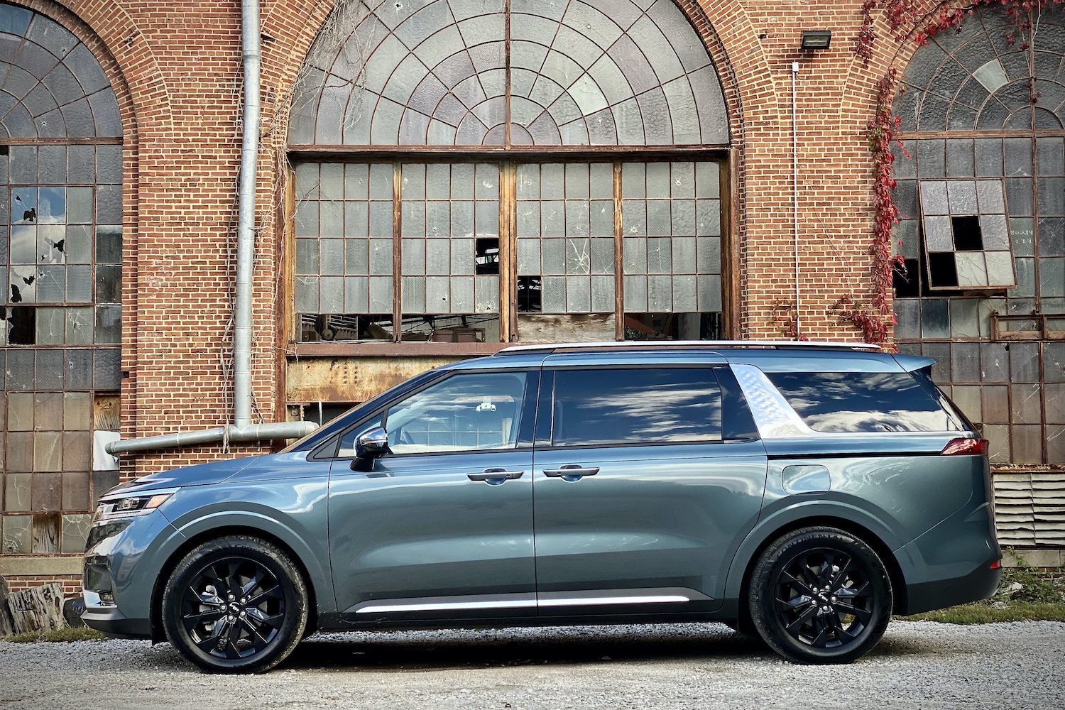 Side profile of Kia Carnival in front of old building.