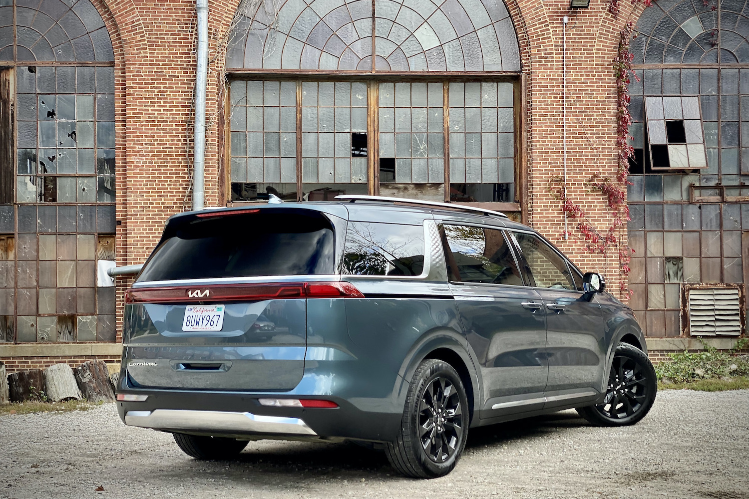 Kia Carnival rear end from passenger angle with old building in the back.