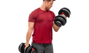 A man does bicep curls using Bowflex SelectTech 552 Adjustable Dumbbells.