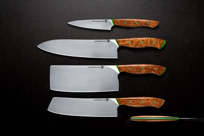 Set of kitchen knives sitting side by side on a black counter.