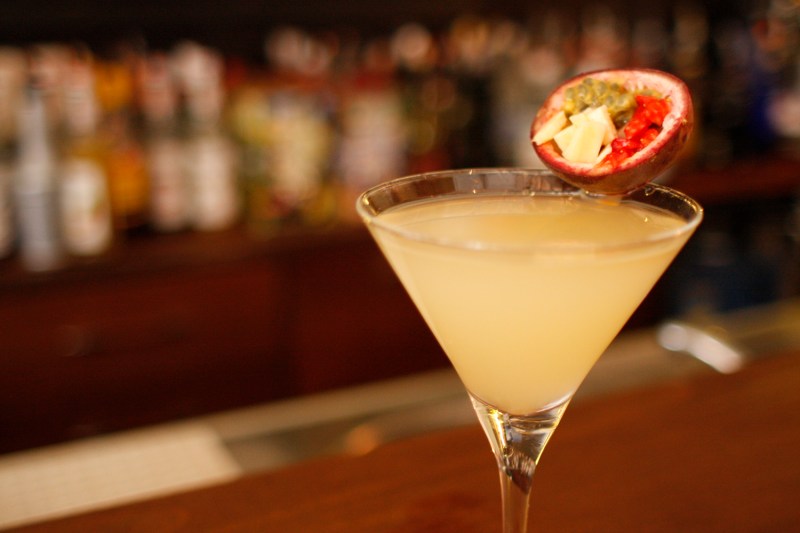 A glass of passion fruit cocktail with garnish in a bar.