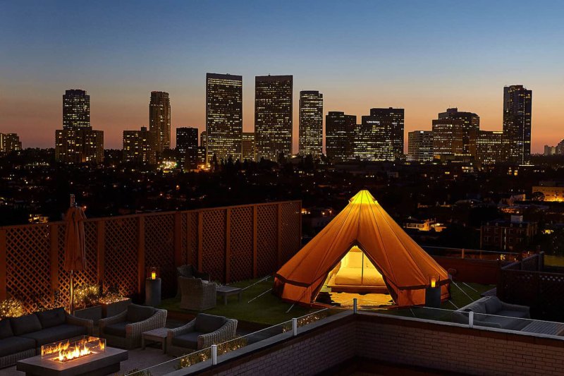 A bird's eve view of skyscrapers and a tent at the veranda in Beverly Wilshire at dusk.