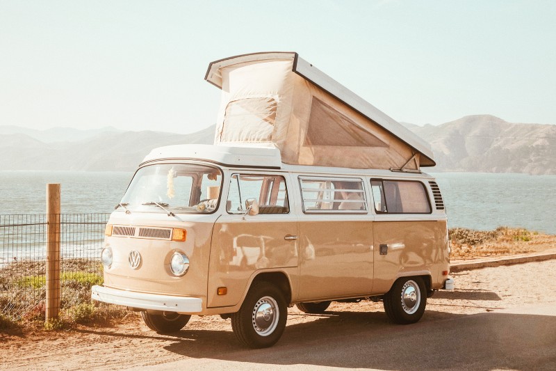 A van parked by the sea during a sunny day.