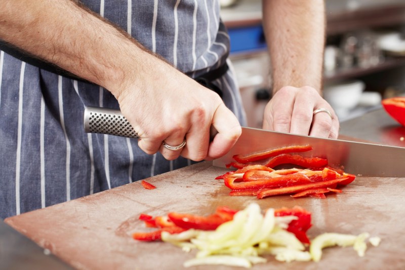 Chef chopping a vegetable with a knife.