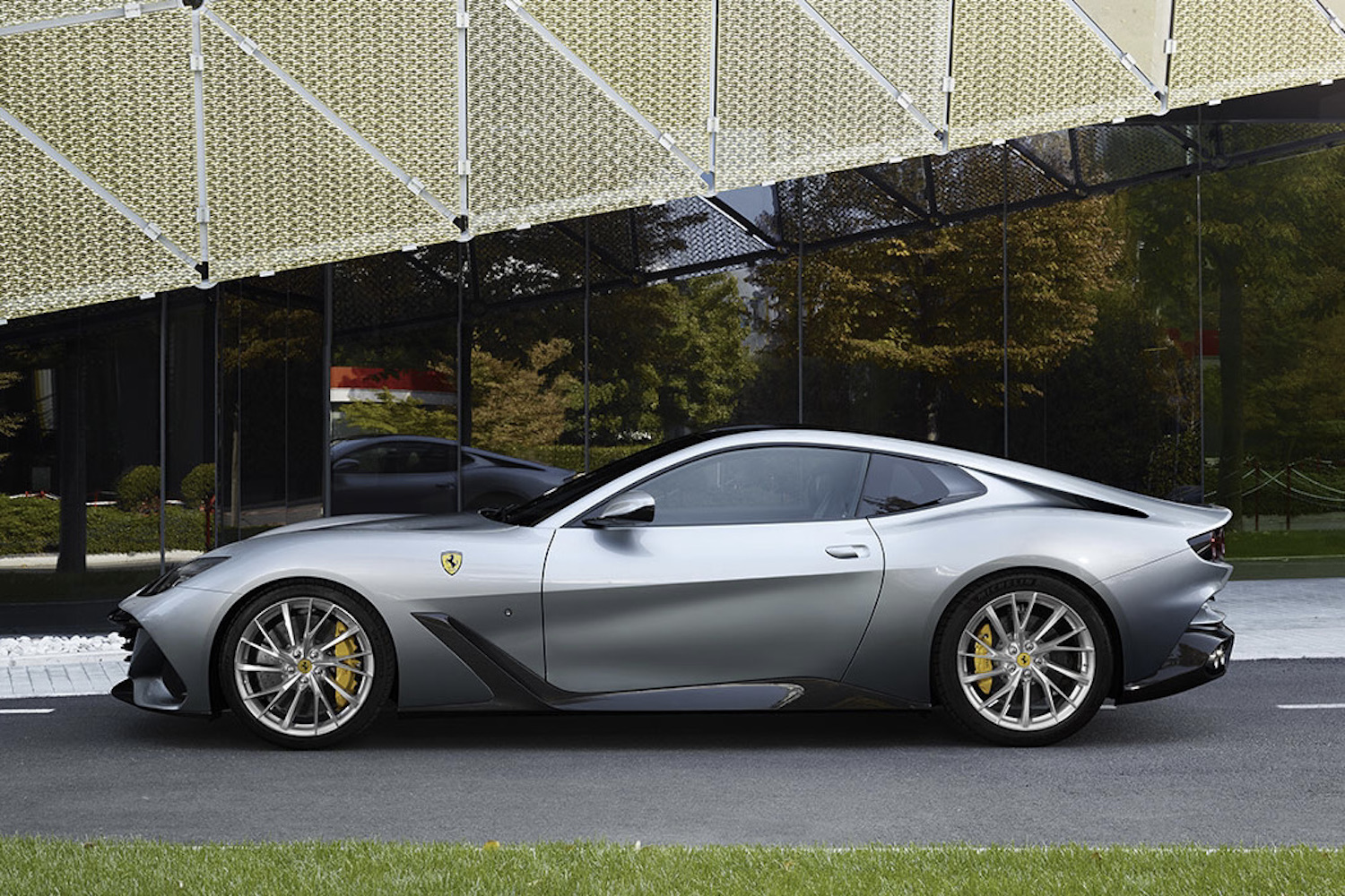 Ferrari BR20 side profile in fron of glass building.