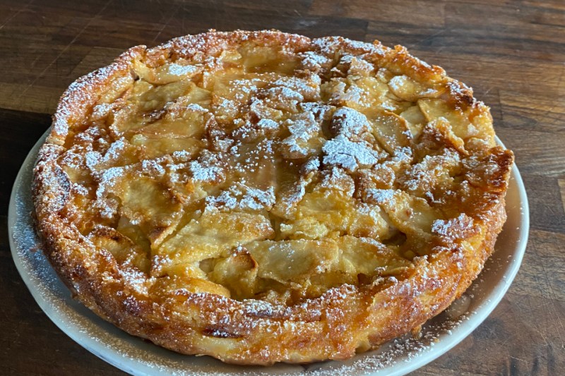 plated French Apple Cake dusted with powdered sugar on table.