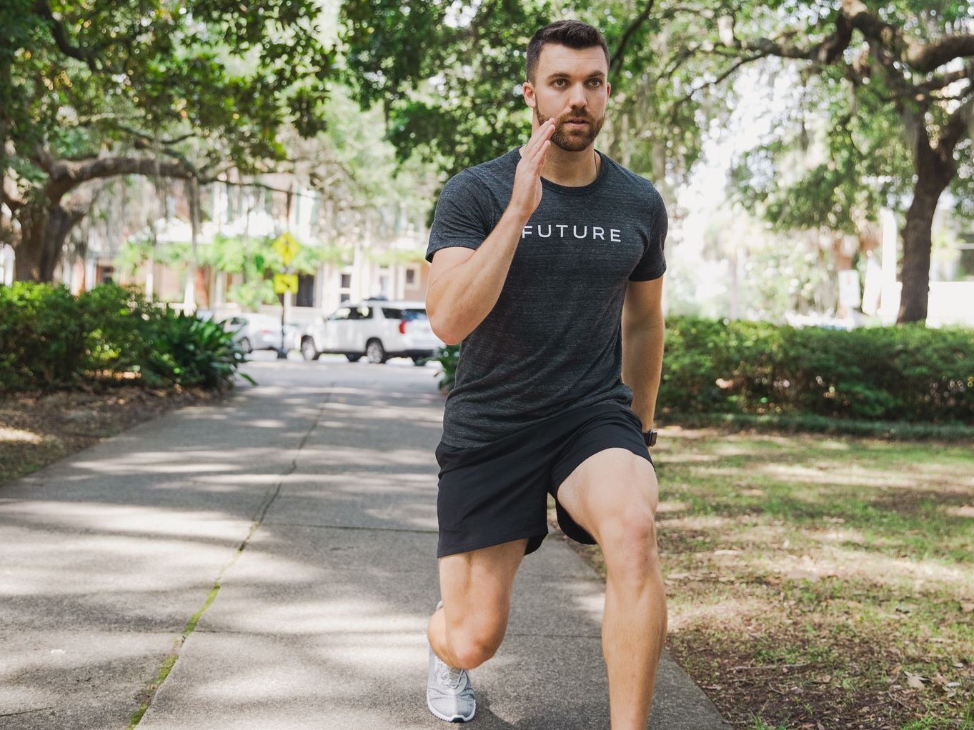 Future coach with Apple Watch doing lunges in park.