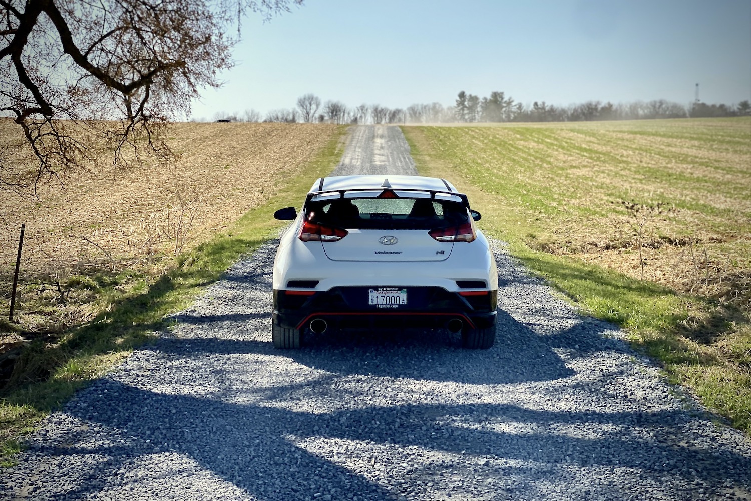 Hyundai Veloster N rear end on a gravel path in a field.