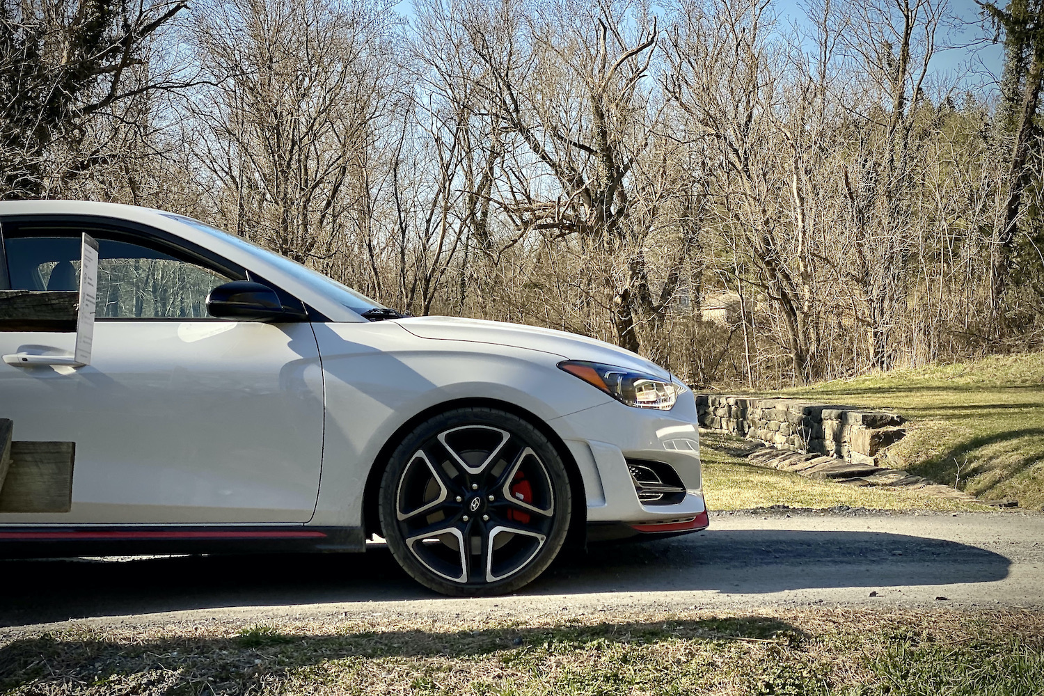 Hyundai Veloster N side of front end on a bridge with trees in the background.