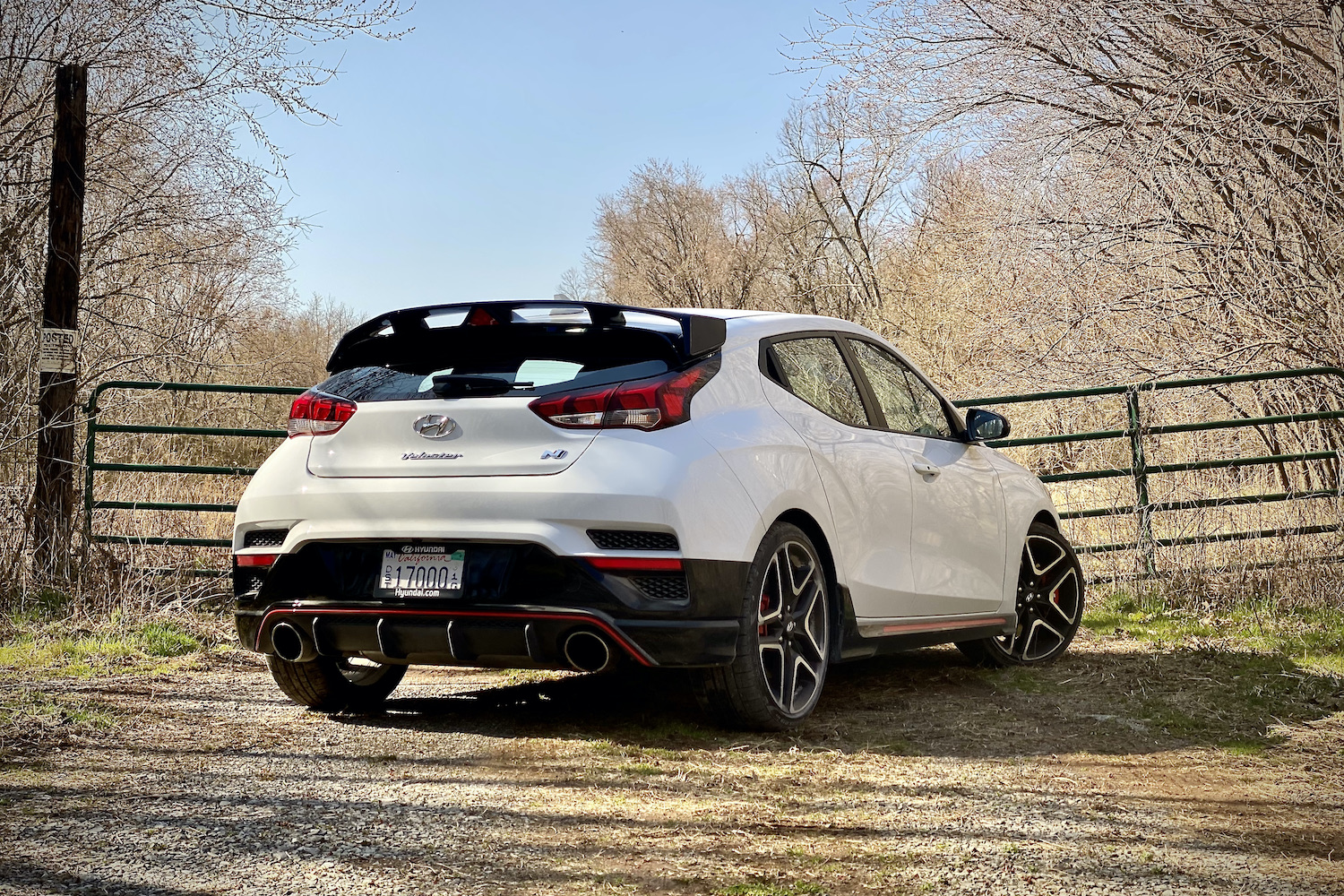 Hyundai Veloster N rear end passenger side in front of fence.