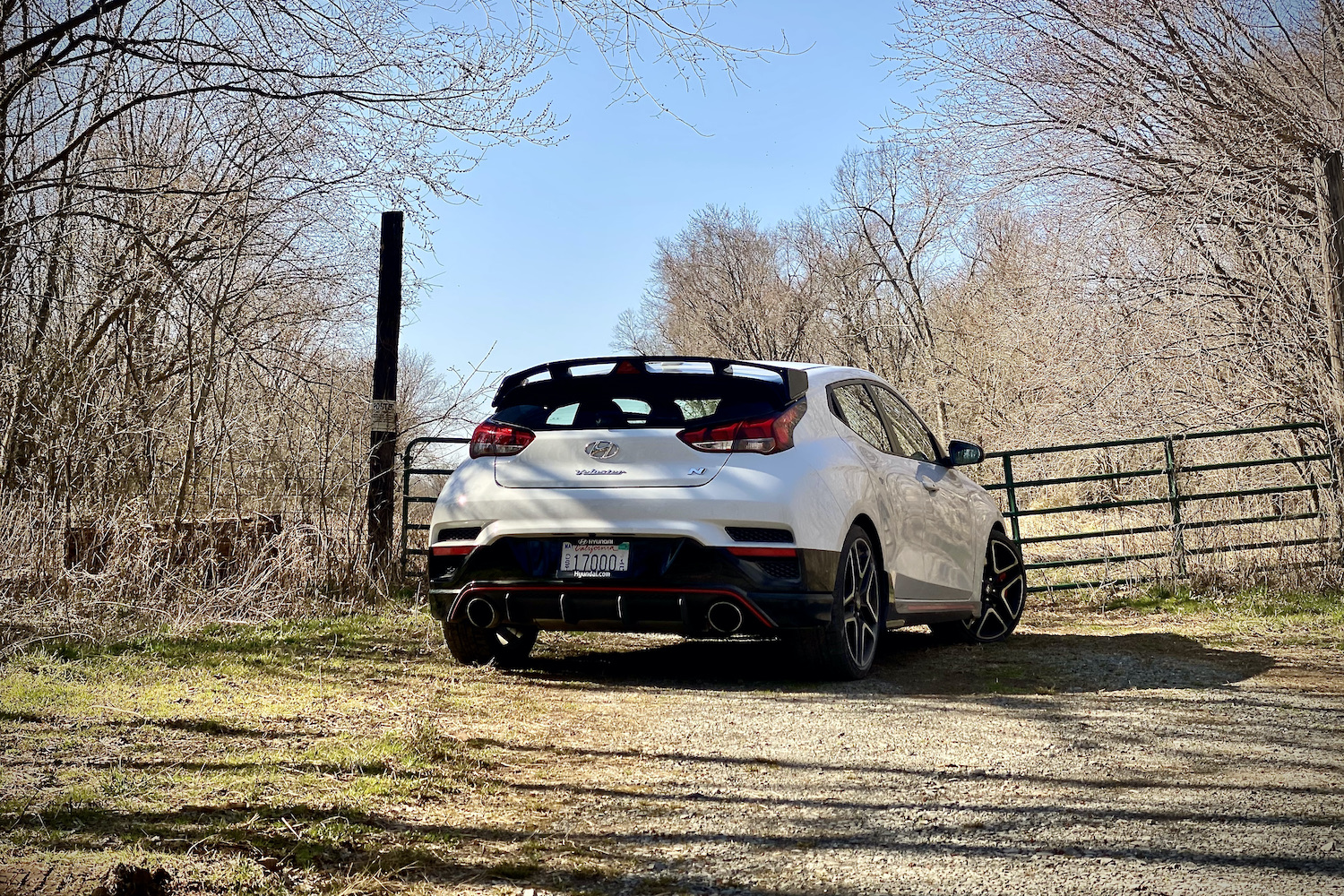 Hyundai Veloster N rear end from passenger side in front of a fence.