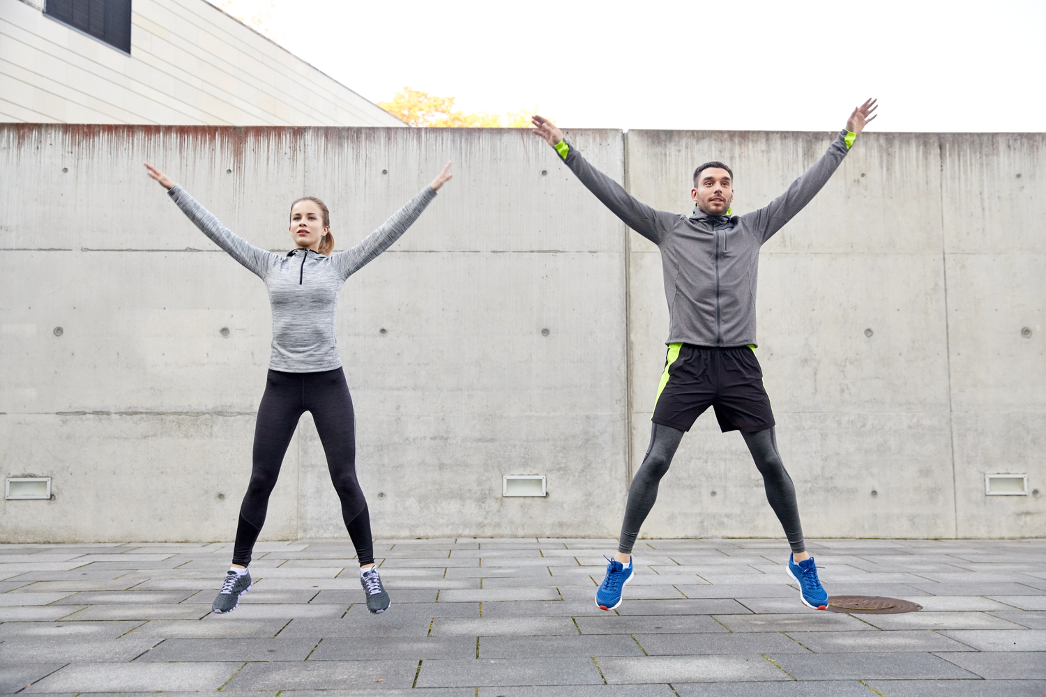 A man and a woman doing jumping jacks.