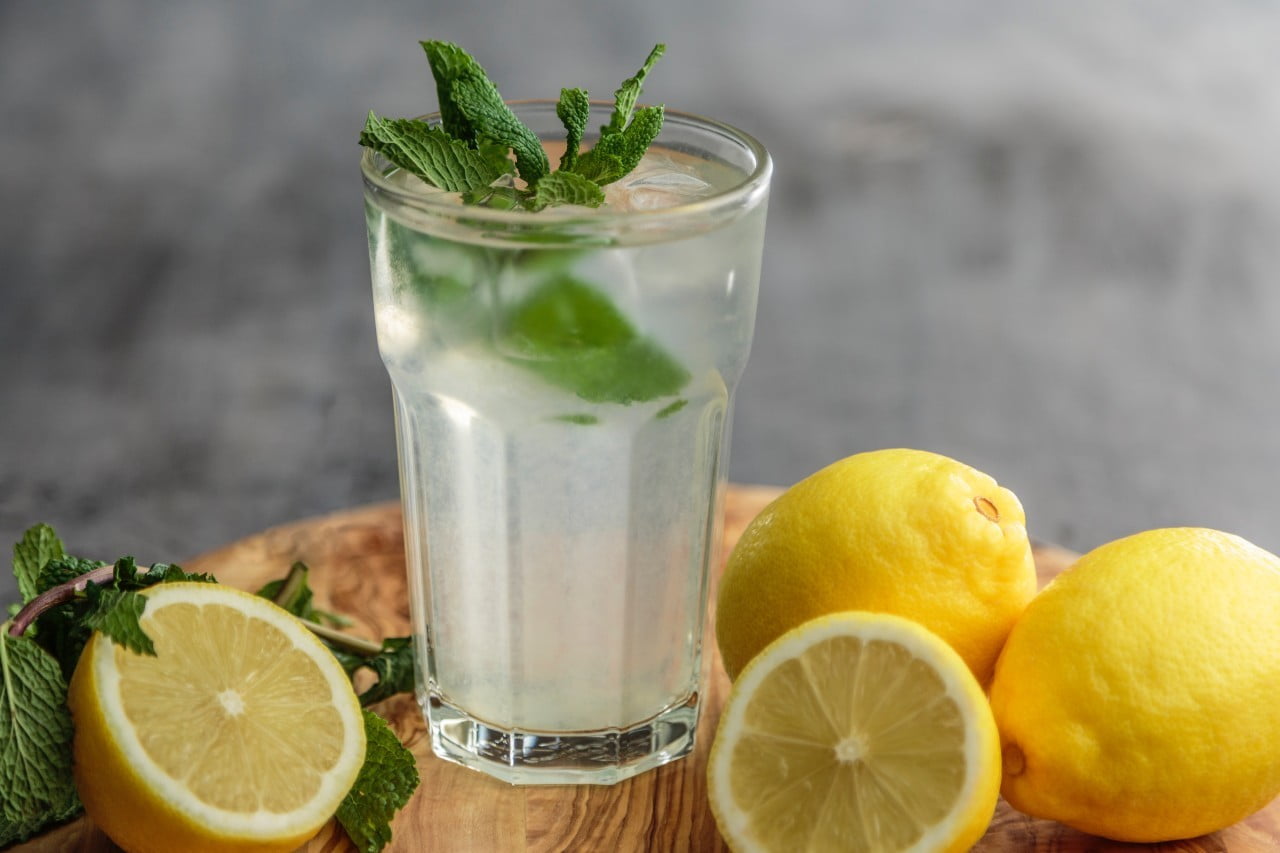 A glass of lemonade surrounded by lemons.