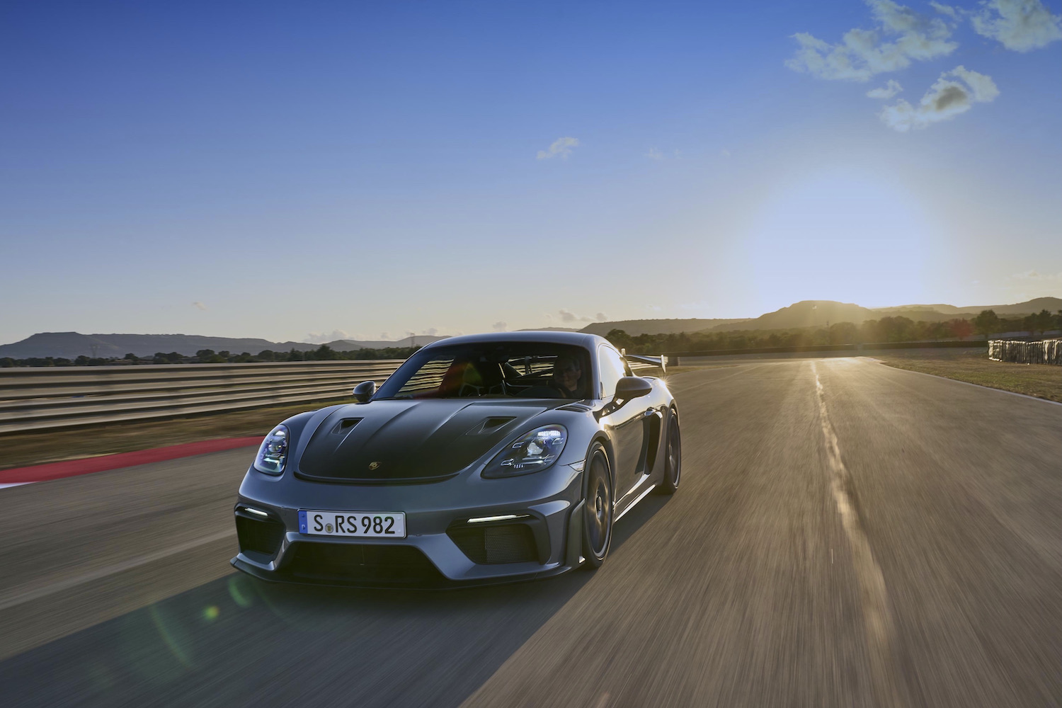 Porsche 718 Cayman GT4 RS front end angle from driver's side on track at sunset.