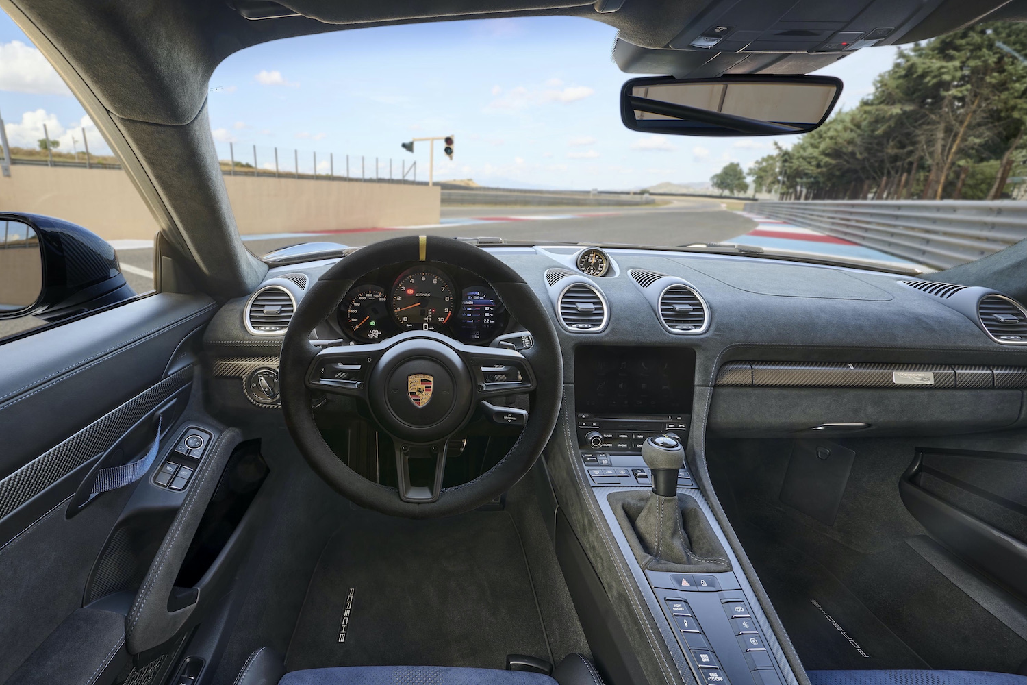 Porsche 718 Cayman GT4 RS interior close up on dashboard and steering wheel on track.