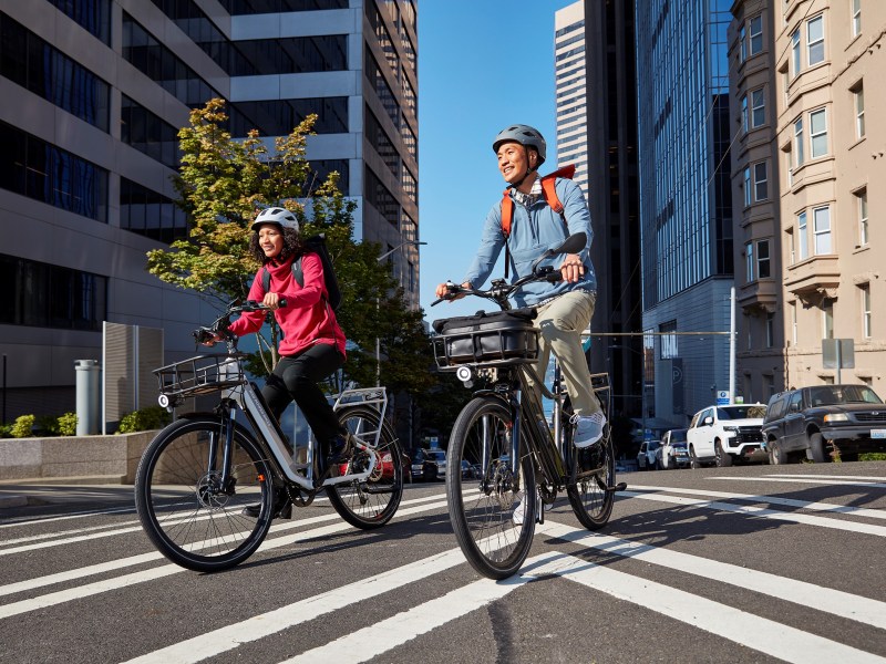 Riders on RadCity 5 Plus e-bike in a city street.