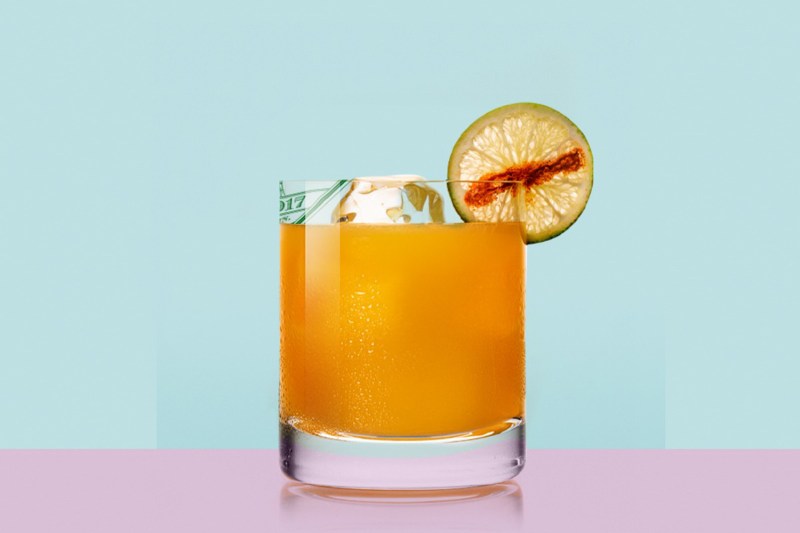 A refreshing glass of Tigre de Valle cocktail with garnish on blue background.