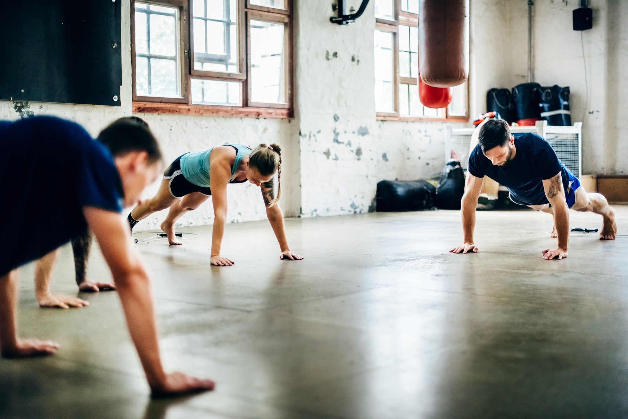 Group of friends doing push-ups at the gym.
