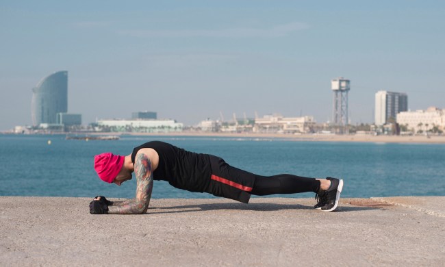 Side view of a man doing up-down planks at a beach.