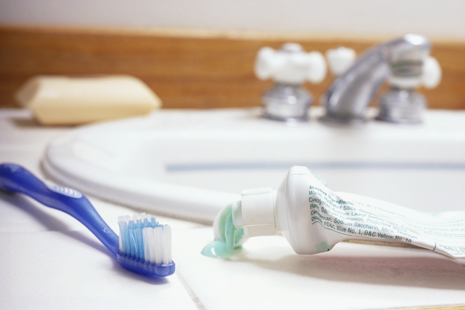 A toothbrush and toothpaste on a sink in a bathroom.