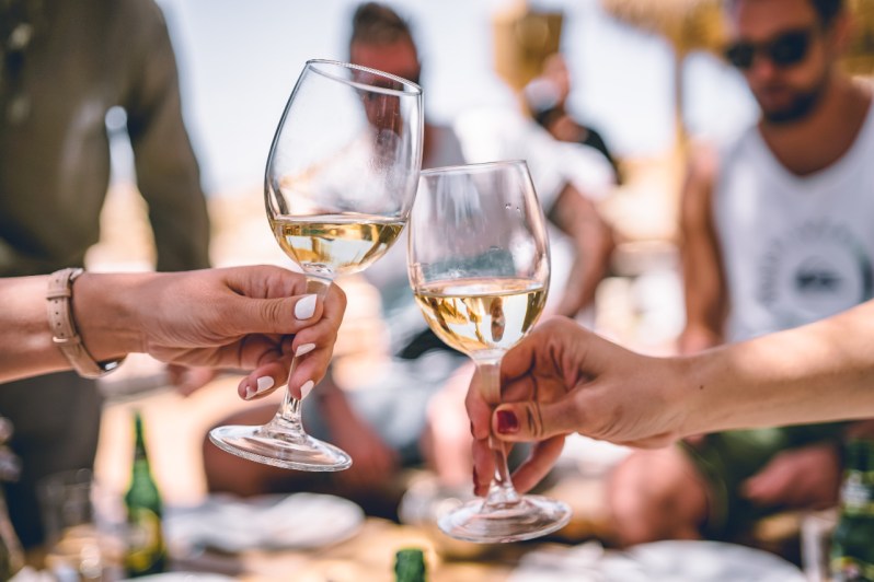 Two white wine glasses cheering outside.