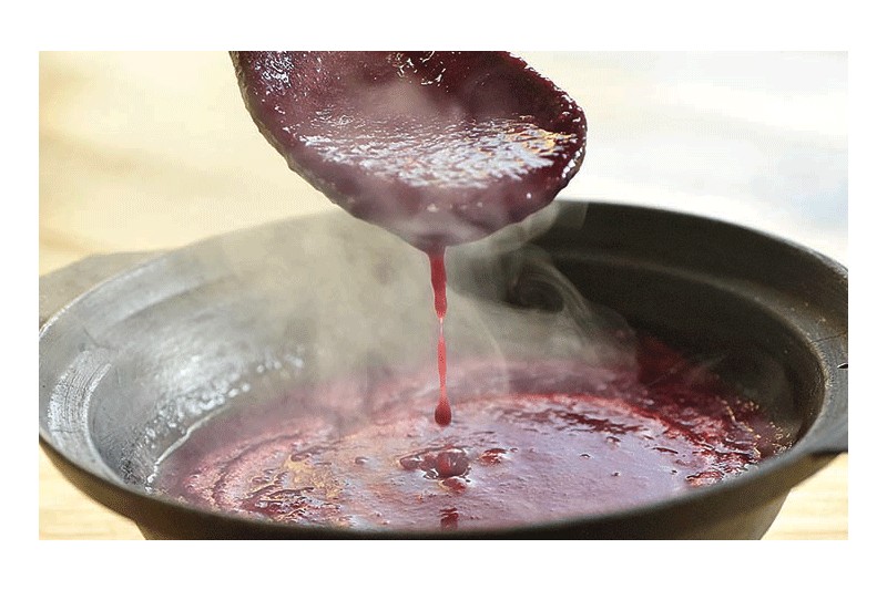 Bowl of wajape cranberry sauce with a spoon dripping the sauce.