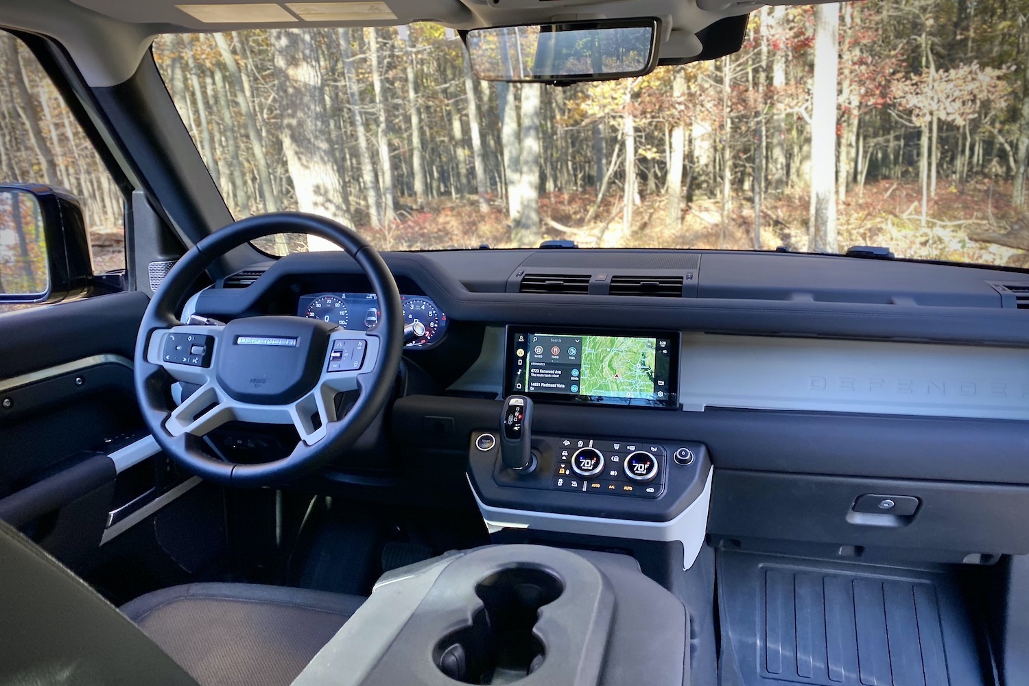 Land Rover Defender dashboard from rear seats with trees in the back.