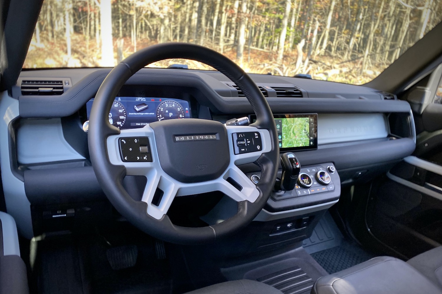 Land Rover Defender dashboard from driver's side with trees in the background.